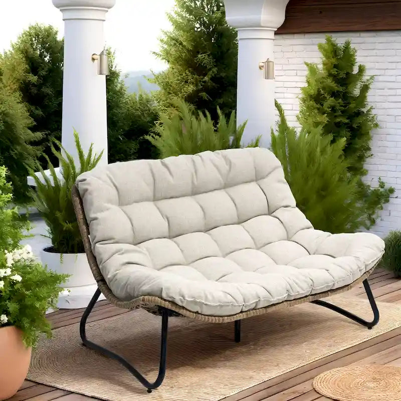 Ce fauteuil double en rotin est livré avec un coussin et convient aussi bien à une utilisation intérieure qu'extérieure.