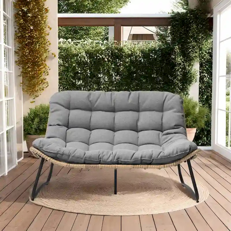 Ce fauteuil double en rotin est livré avec un coussin et convient aussi bien à une utilisation intérieure qu'extérieure.