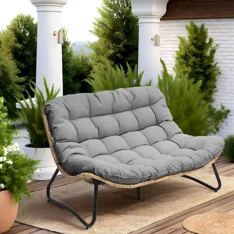 Ce fauteuil double en rotin est livré avec un coussin et convient aussi bien à une utilisation intérieure qu'extérieure.